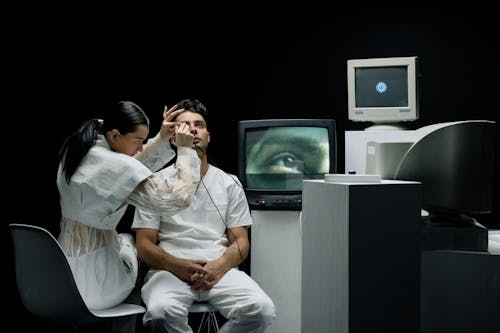 Woman in White Clothing Checking Man's Eye