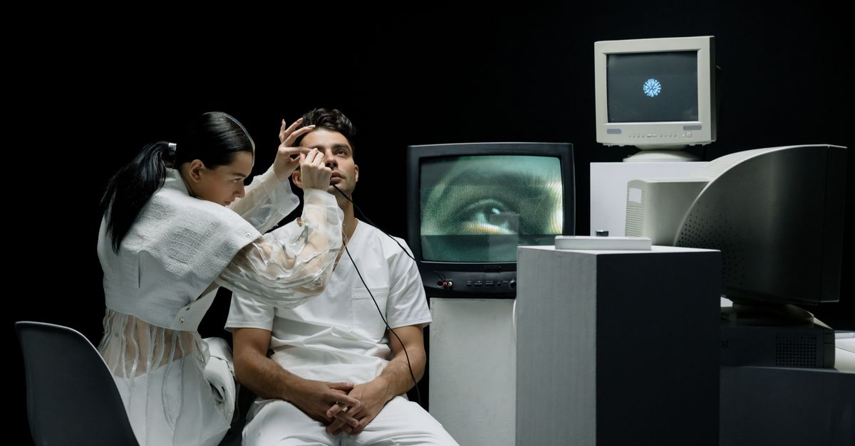 A woman performs an eye examination on a man in a vintage tech lab.