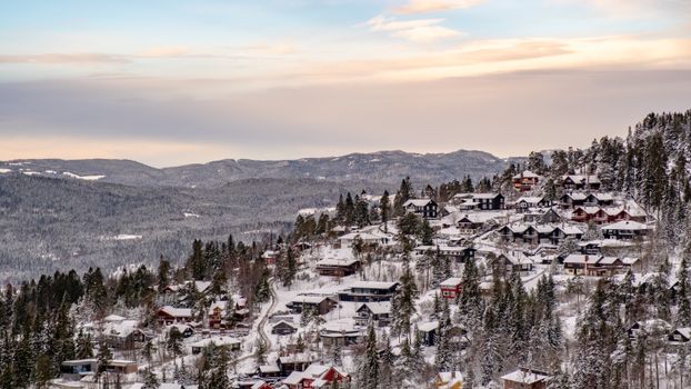 A stunning winter view of a snowy village nestled in mountainous terrain under a serene sky.