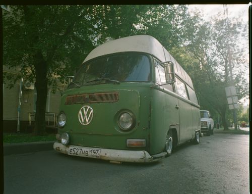 Free Classic retro Volkswagen van parked on a city street with trees in the background. Stock Photo