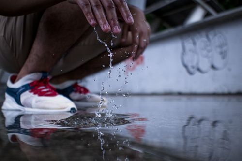 Free A person splashes water on the ground, capturing the dynamic motion of water droplets. Stock Photo