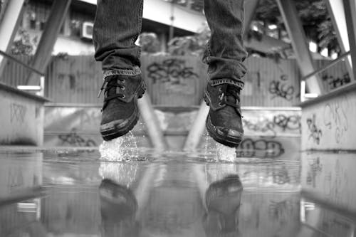 Monochrome Photo of a Person's Feet Jumping Off the Ground