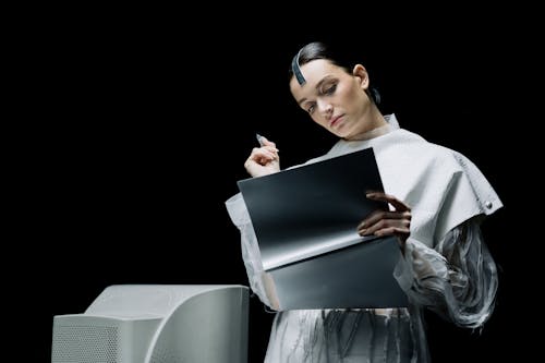 Woman Holding a Pen While Looking at a Folder