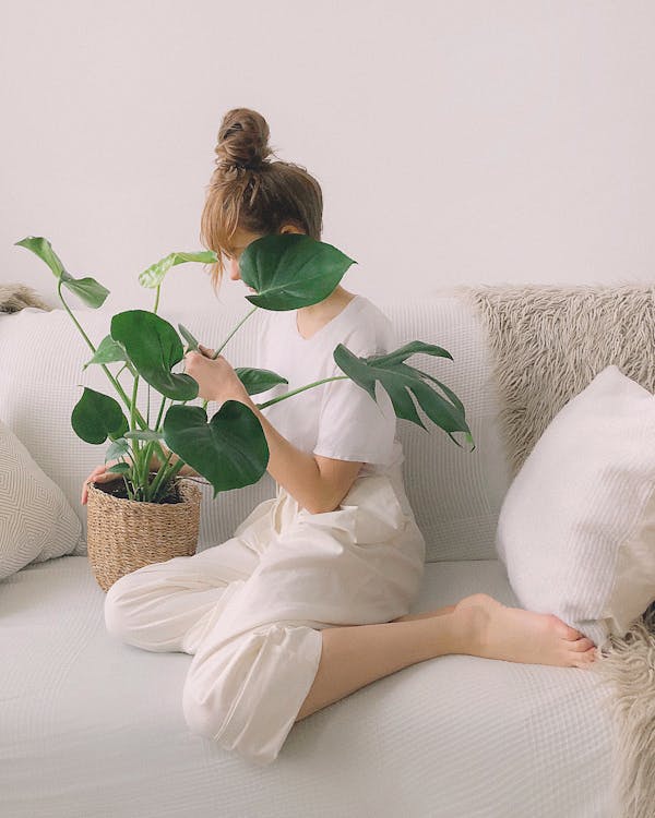 Woman Wearing White Crew-neck Shirt and White Pants While Sitting on White Couch