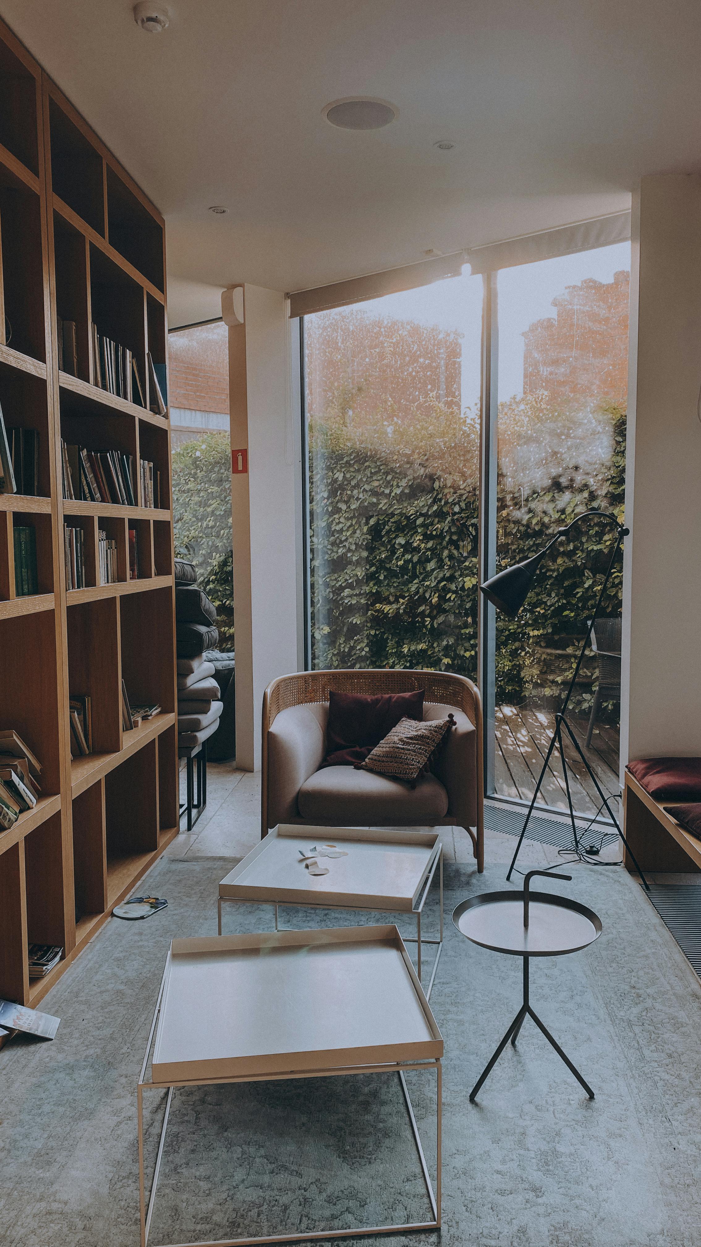 Free Inviting living room with bookshelves, a cozy chair, and stylish tables, perfect for relaxation. Stock Photo