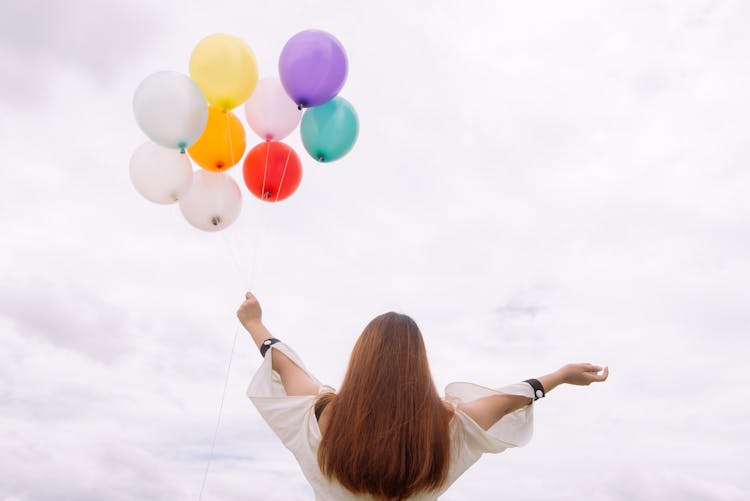 Worm's-eye View Of Woman Holding Balloons