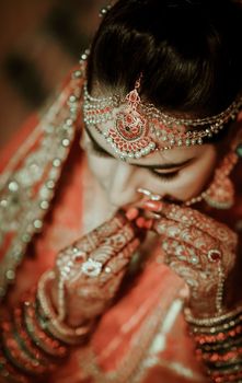 An Indian bride adorned with traditional jewelry and intricate mehndi designs, portraying elegance and cultural richness.