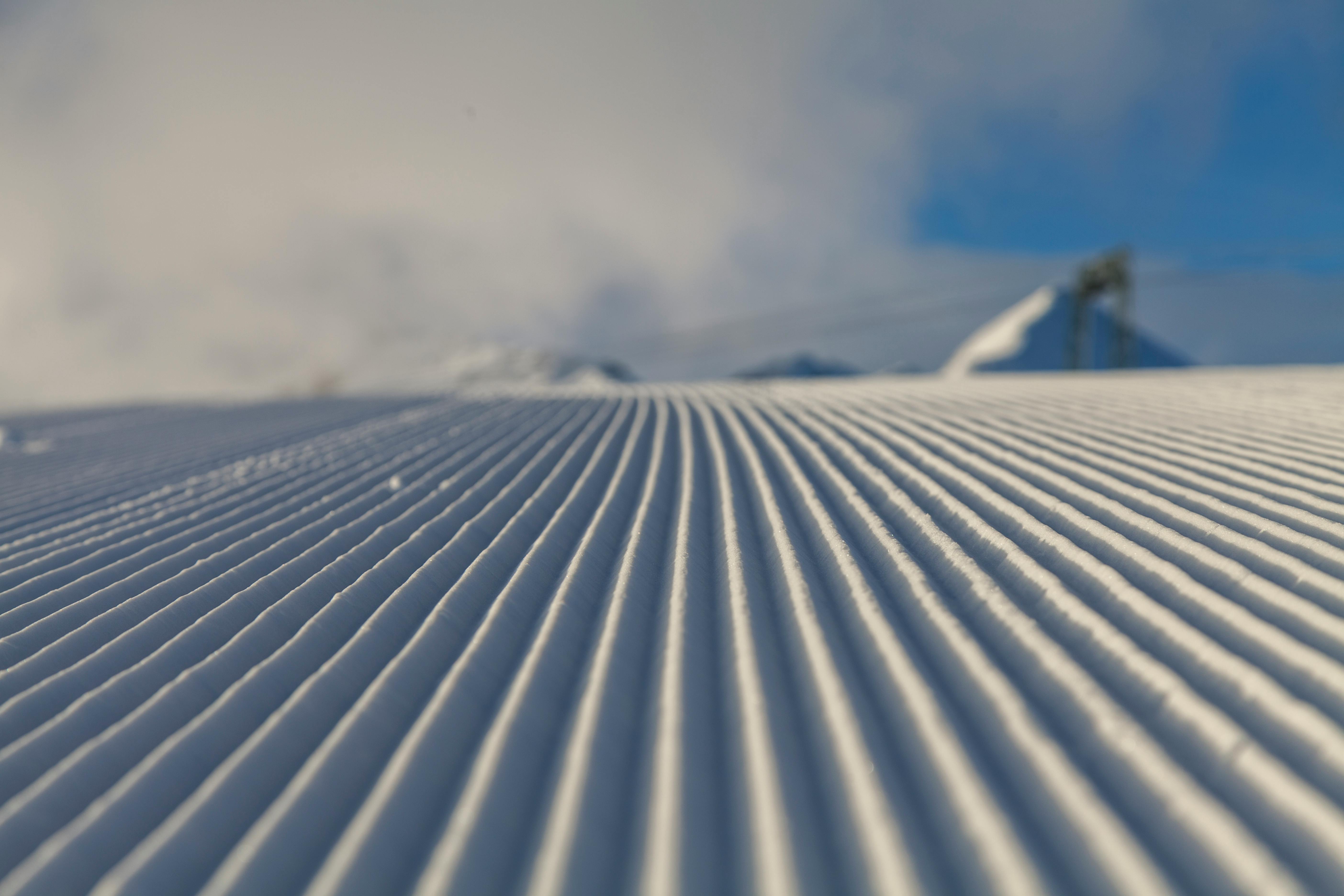 Prescription Goggle Inserts - A scenic view of a freshly groomed ski slope under clear winter skies, ideal for skiing.