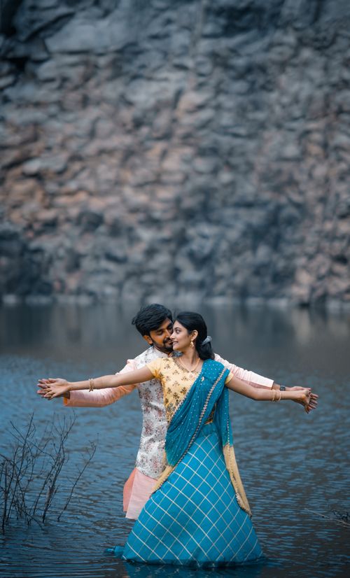 Free Romantic couple embracing by the water in traditional attire, evoking love and serenity. Stock Photo