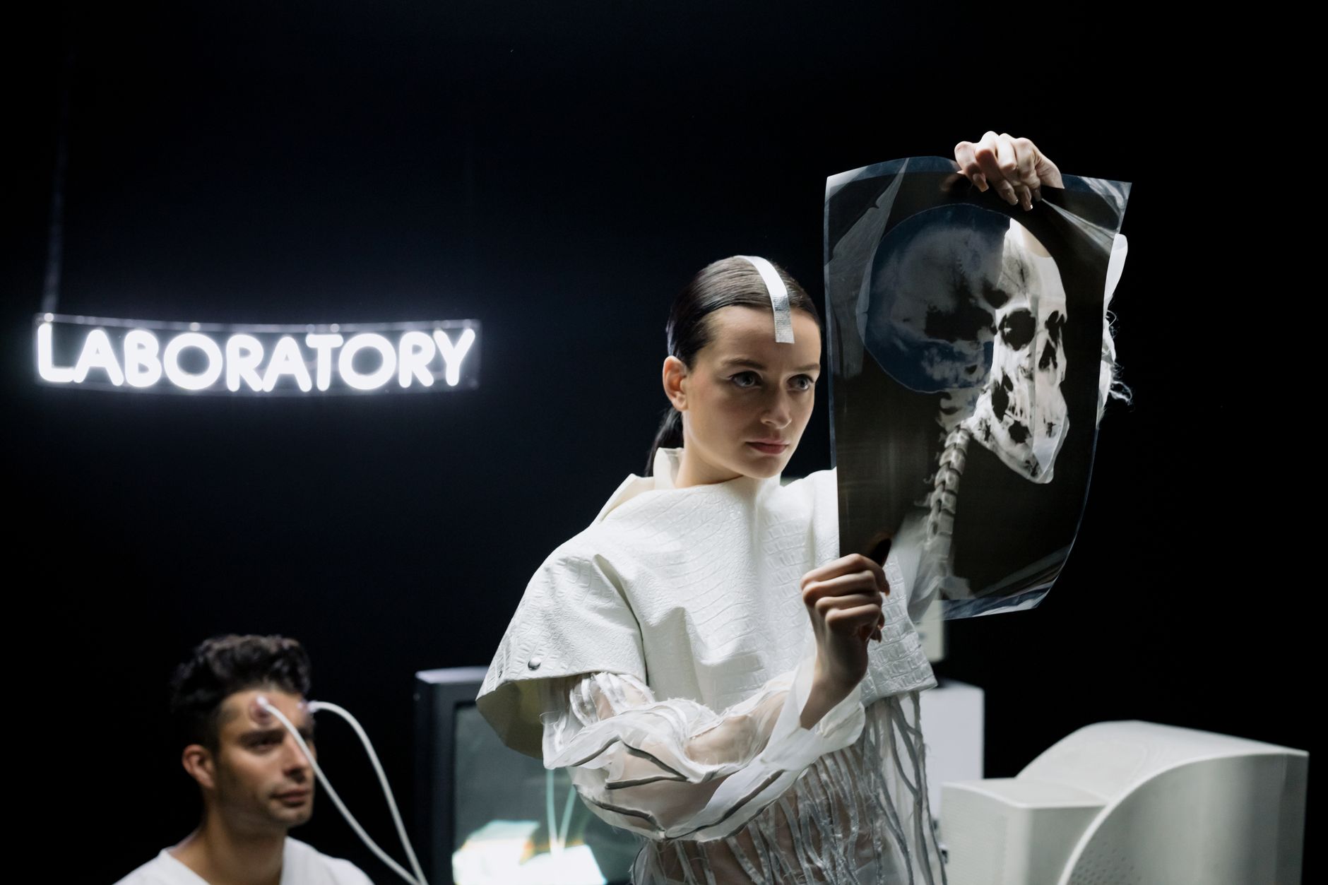 A woman examines an X-ray in a futuristic laboratory setting with neon lights.