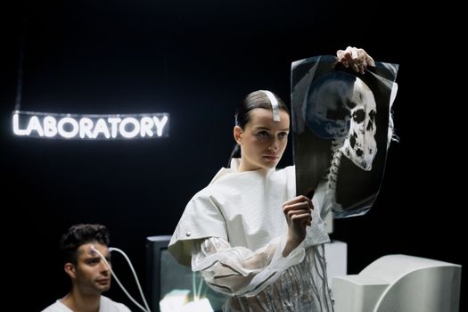 A woman examines an X-ray in a futuristic laboratory setting with neon lights.