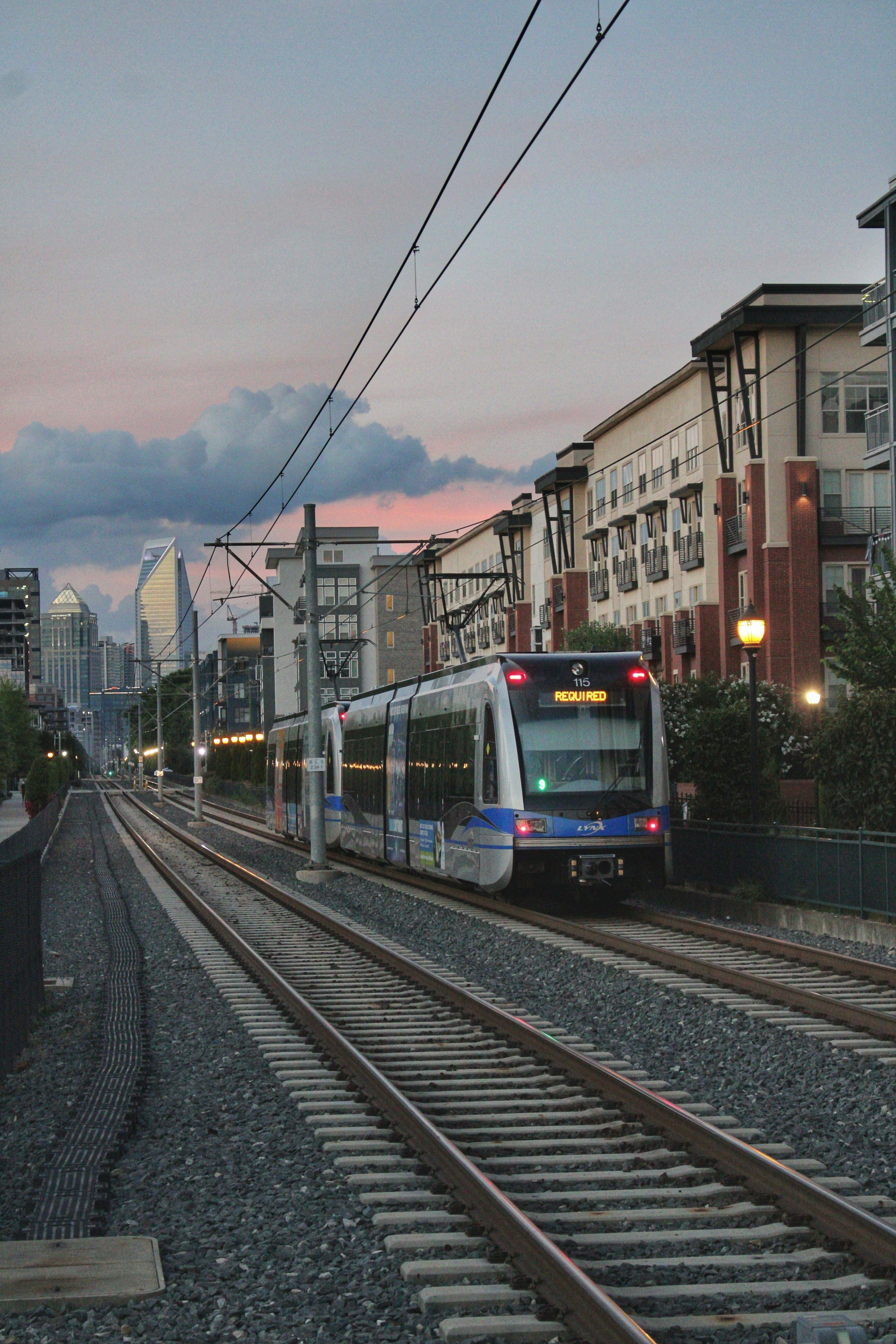 Free A modern city train travels along railway tracks during a picturesque sunset in an urban setting. Stock Photo