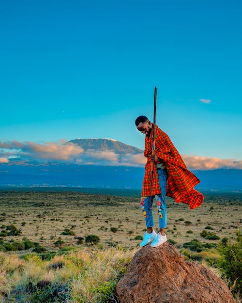 Man Standing on a Rock with a Mountain in Distance 