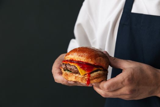 A savory cheeseburger with dripping ketchup held in hands, emphasizing the juicy flavor.