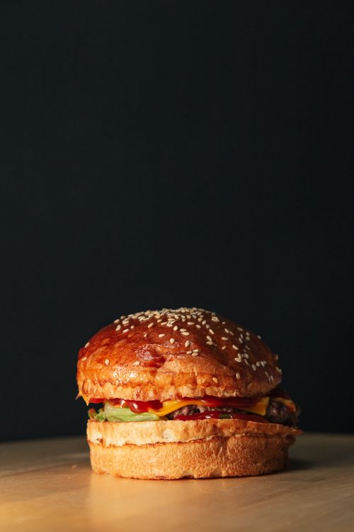 Free A mouth-watering cheeseburger with sesame seed bun on wooden table. Stock Photo