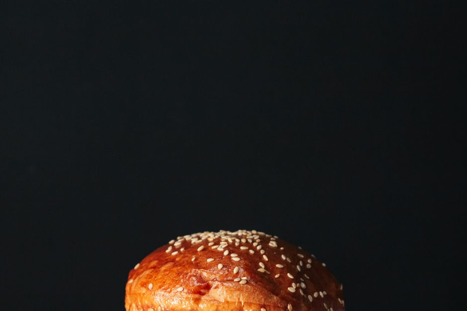 Close-up of a delicious sesame seed burger bun against a dark backdrop, perfect for food photography.