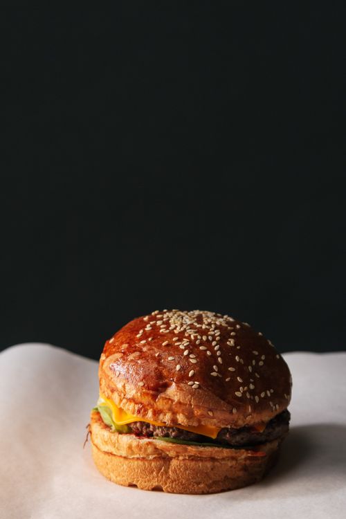 Free Close-up of a delicious cheeseburger on a dark background with ample copy space. Stock Photo