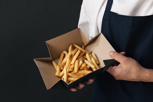 Chef holding a cardboard box of delicious French fries.