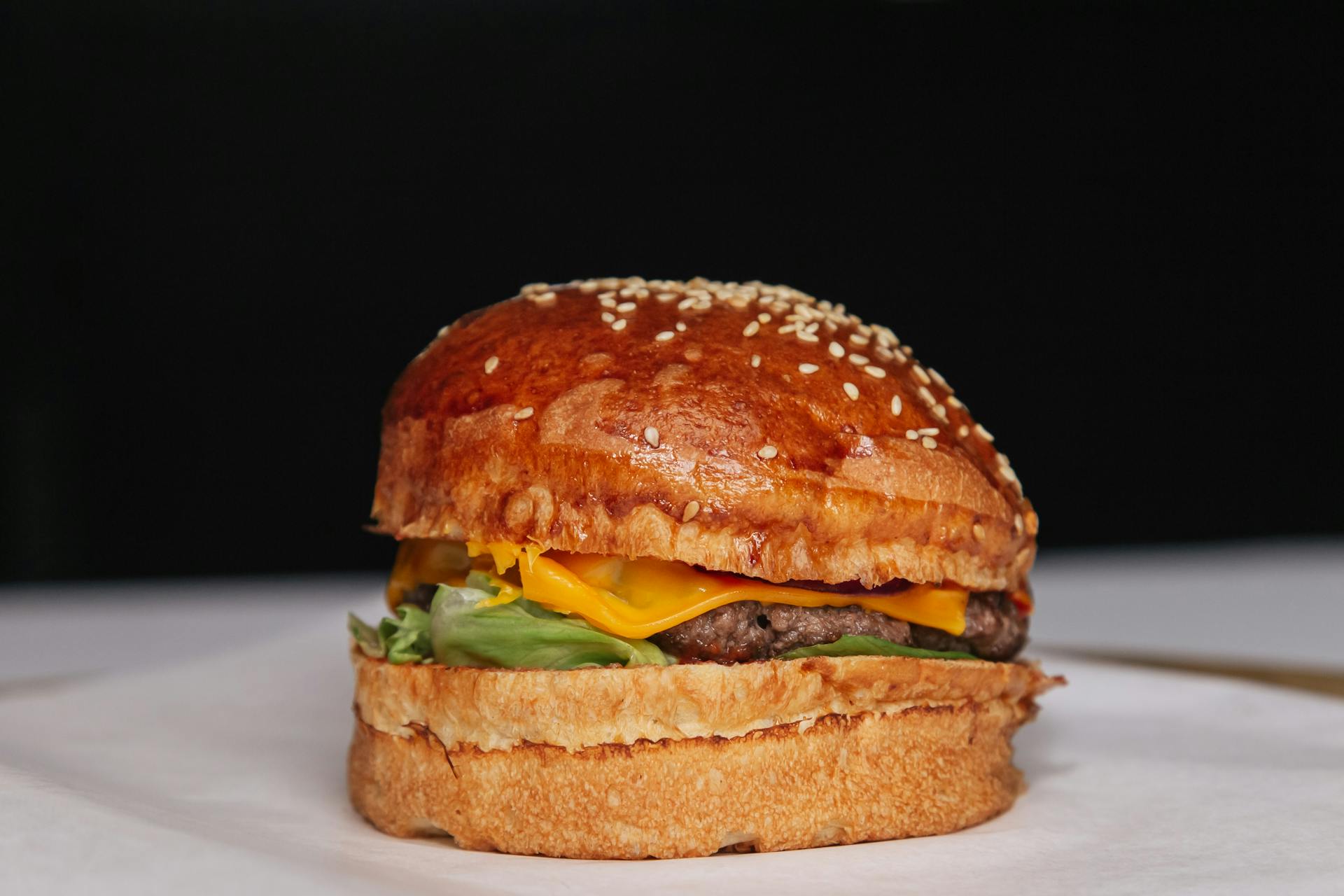 A Delicious Cheeseburger with Lettuce in a Sesame Bun