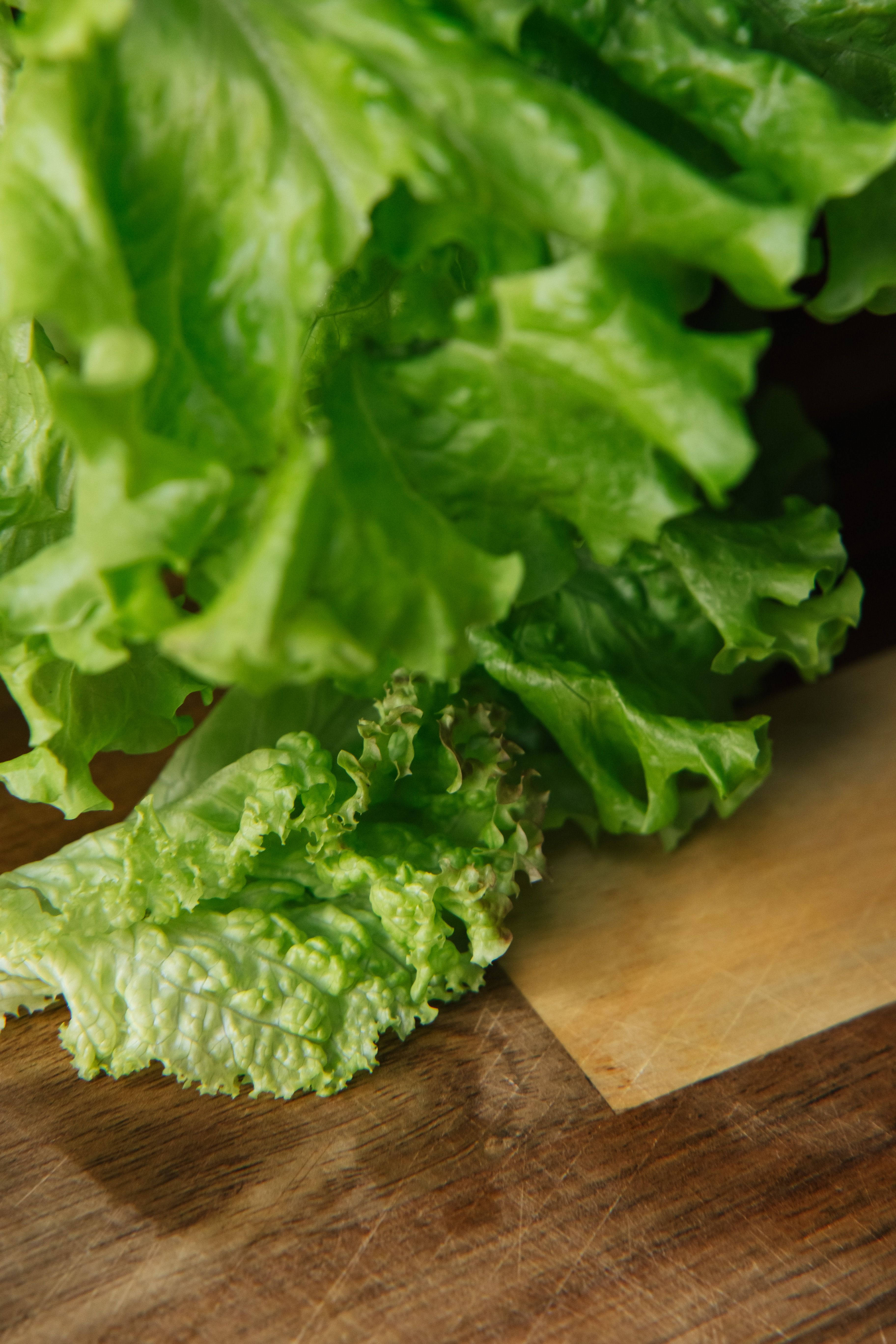 Crisp green lettuce leaves placed on a wooden cutting board, ready for a fresh salad.