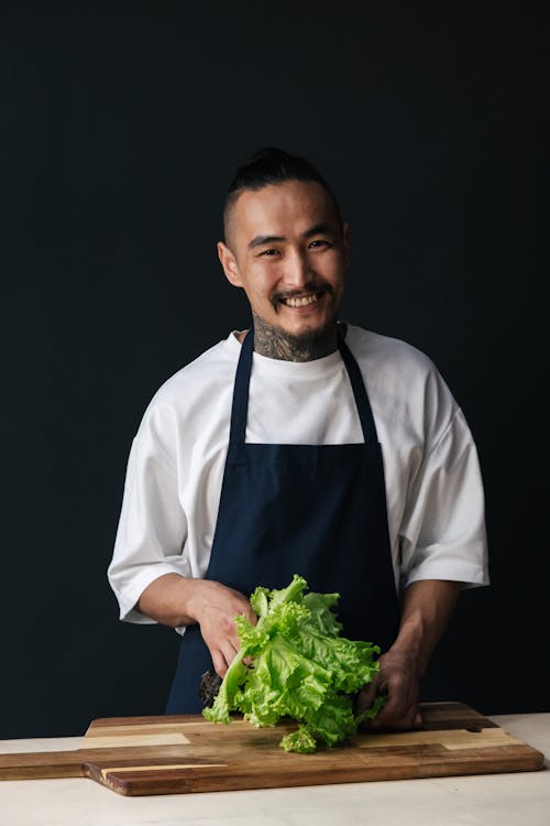 Photo of a Man Smiling while Holding Green Lettuce