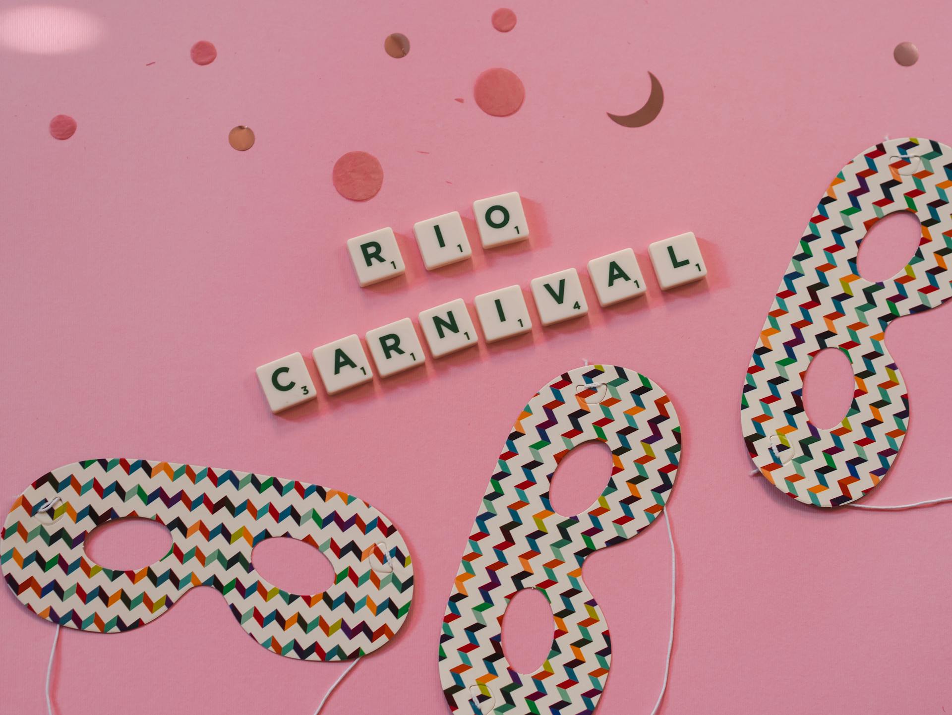 Festive Rio Carnival layout with colorful masks and scrabble tiles spelling 'Rio Carnival' on a pink background.