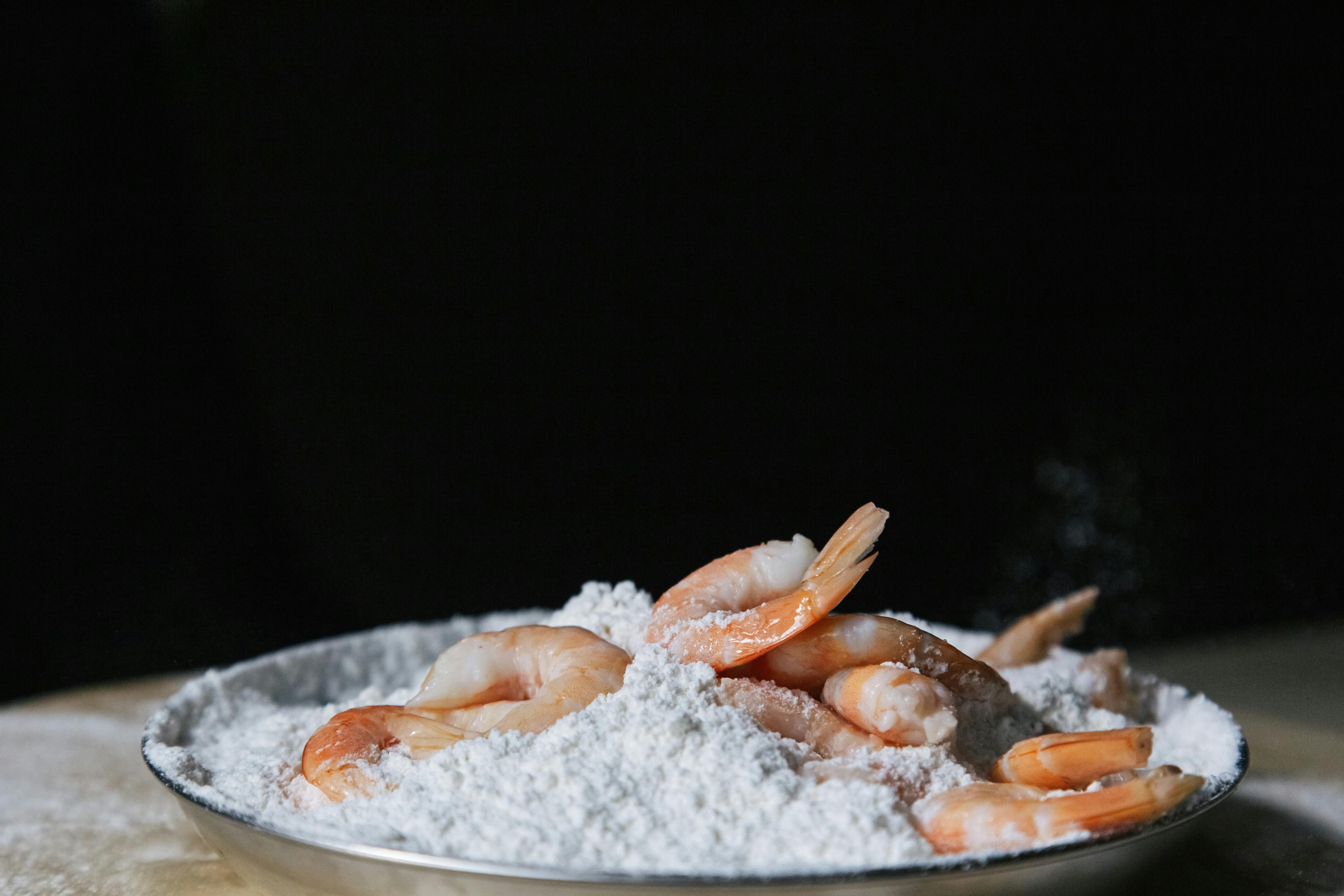 A close-up view of fresh shrimps placed on a bed of flour, ideal for food photography and culinary themes.