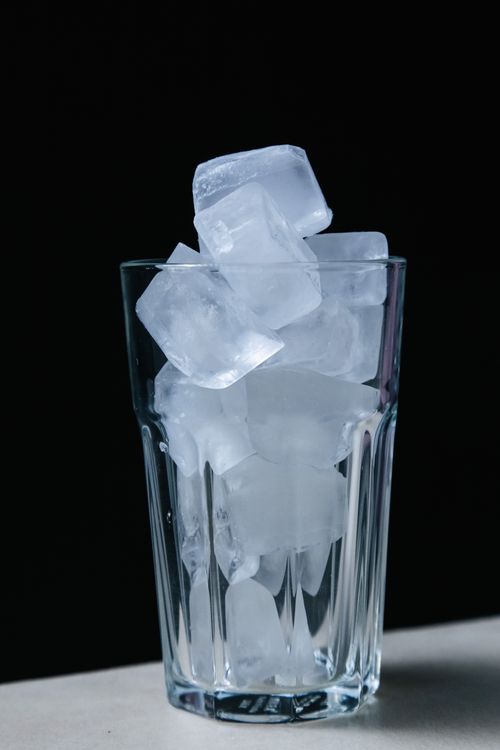Free Chilled ice cubes stacked in a clear glass against a black background, perfect for summer themes. Stock Photo