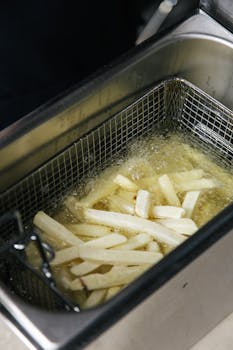 Close-up of french fries cooking in a deep fryer with bubbling oil.