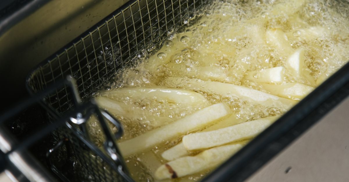 Close-up de batatas fritas sendo fritas em uma fritadeira, estalando no óleo.