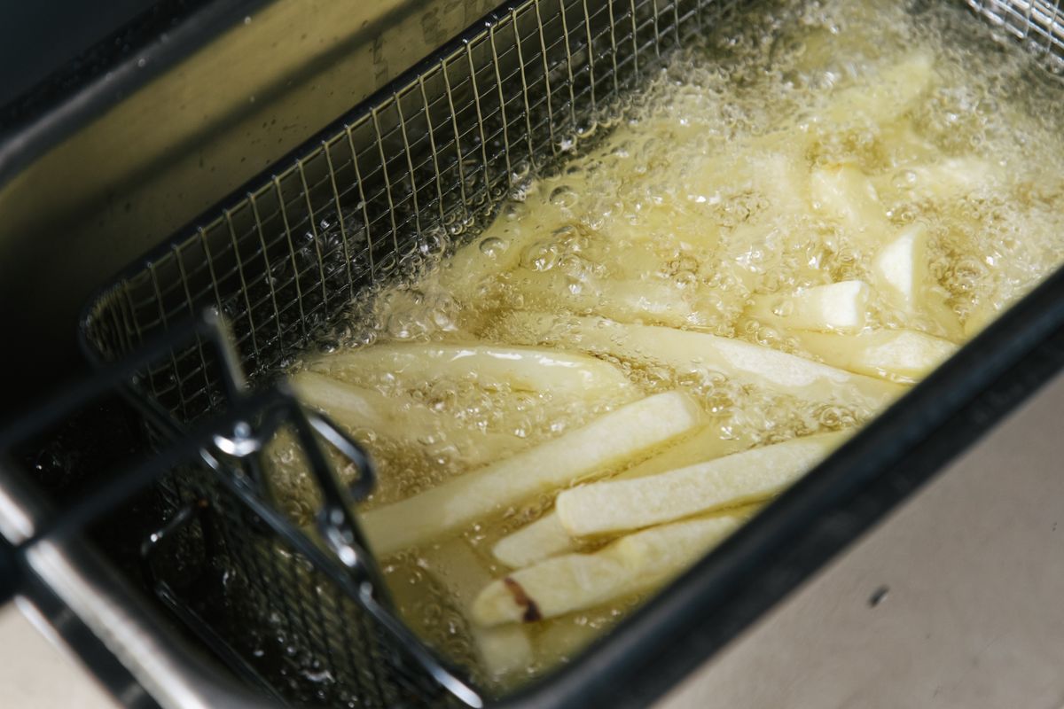 Chef working with a commercial fryer in a kitchen