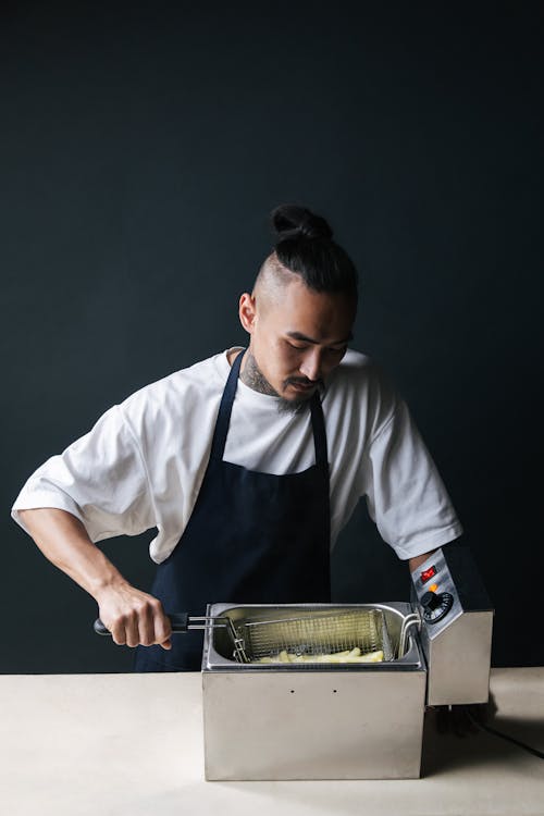 Photo of a Man in a White Shirt Frying French Fries