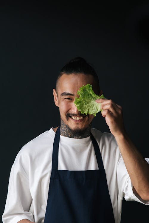 A Happy Male Chef Holding a Lettuce while Looking at Camera