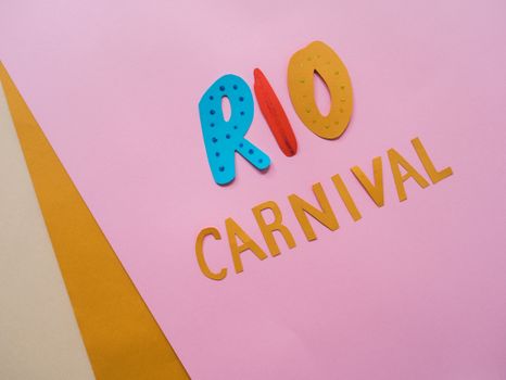 Creative paper cut out design with vibrant colors spelling Rio Carnival on pink background.
