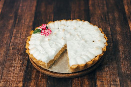 Close-up of a delicious creamy pie with flower decoration on wood.