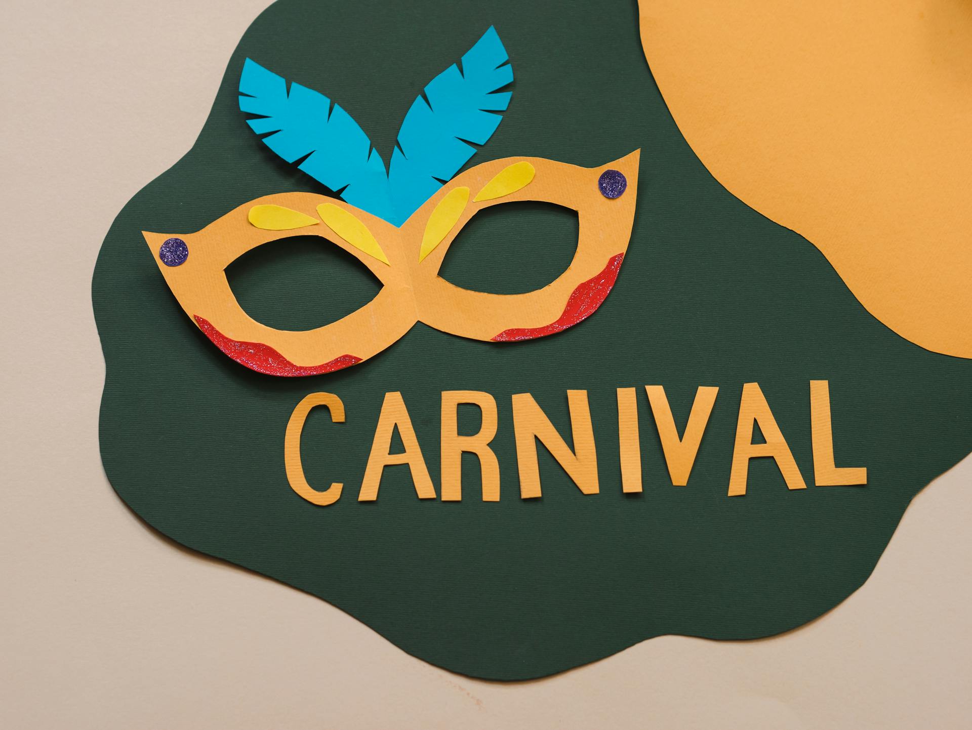 Vibrant paper cutout carnival mask with feathers and bold text on a colorful background.