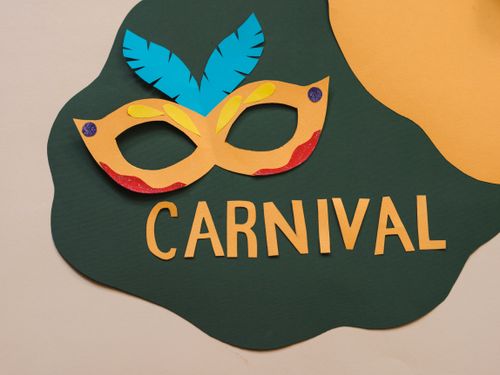 Free Vibrant paper cutout carnival mask with feathers and bold text on a colorful background. Stock Photo