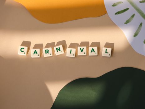 Scrabble tiles spelling 'Carnival' on colorful paper backdrop with shadow play.