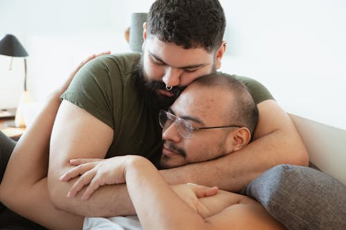 Photo of a Man with Facial Hair Hugging a Man with Eyeglasses