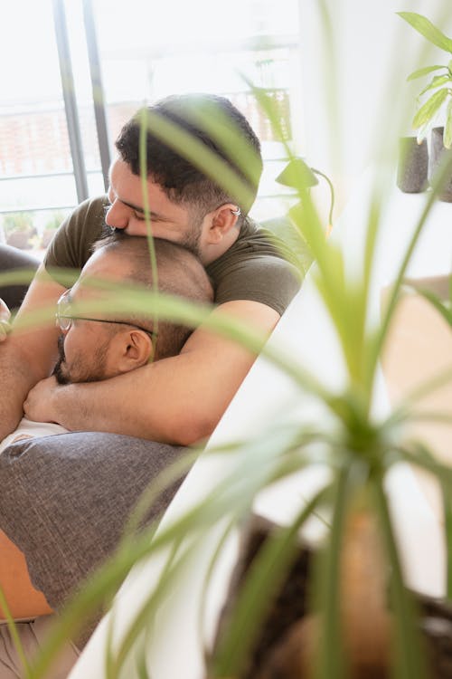 Free Photo of a Man in a Green Shirt Hugging a Man on a Sofa Stock Photo