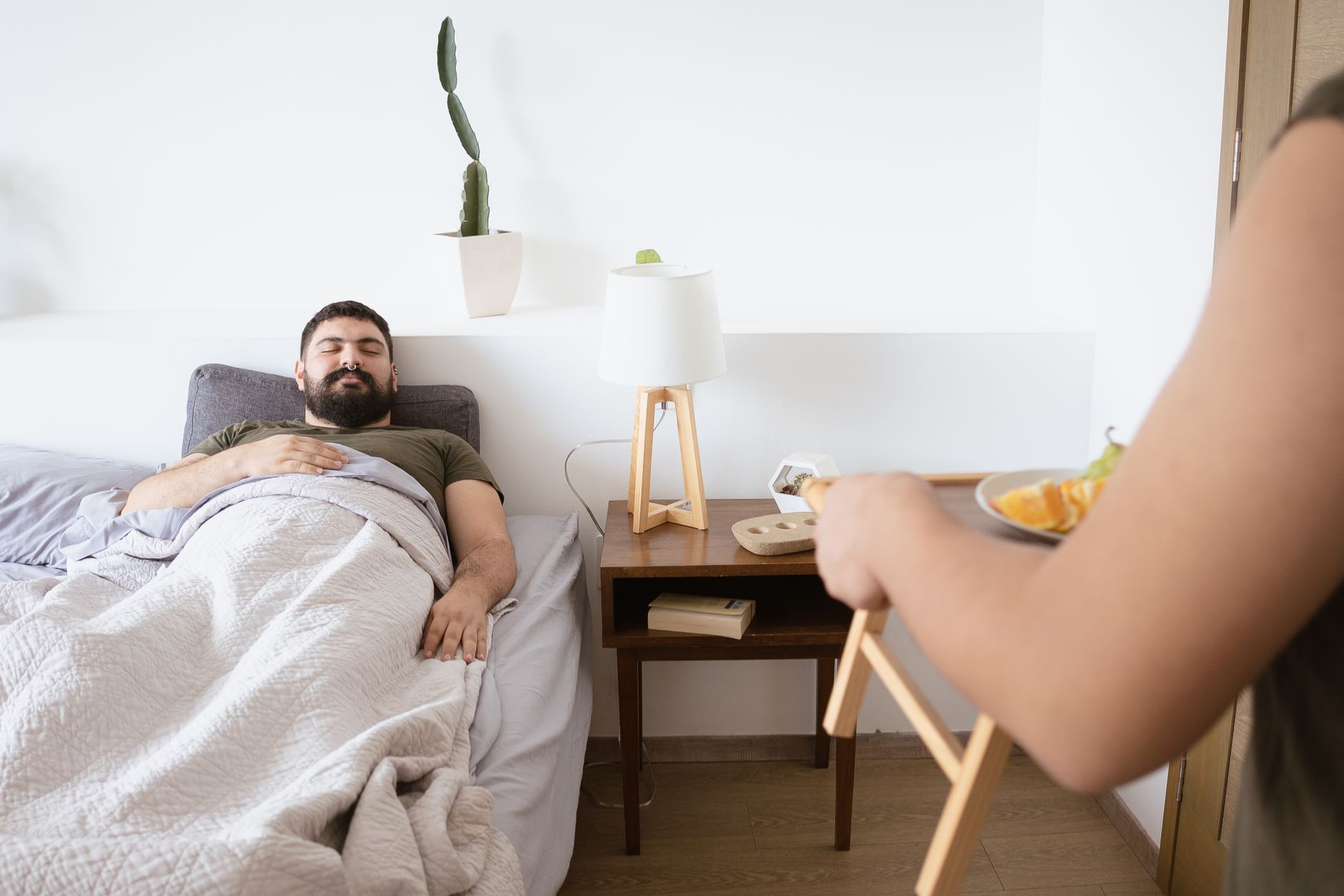 Man enjoying a cozy morning in a clean bedroom with minimal bedroom decor and fresh air