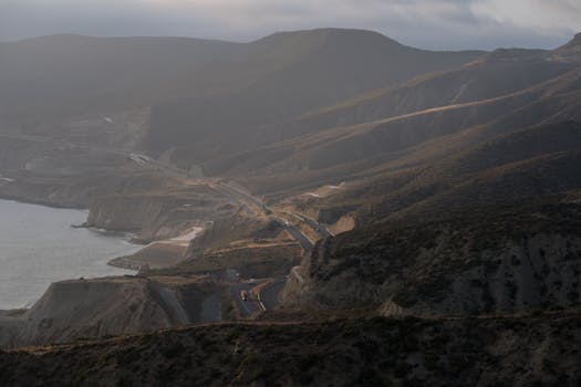 Dramatic aerial view of winding coastal roads through Guadalupe's hills at dusk.