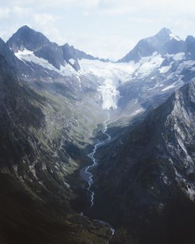 Explore the stunning snowy peaks and glacier streams of Dombay, Russia from above. Ideal for winter scenery lovers.