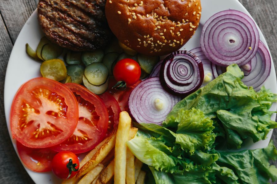 Burger style beef meal with vegetables pickles and potatoes