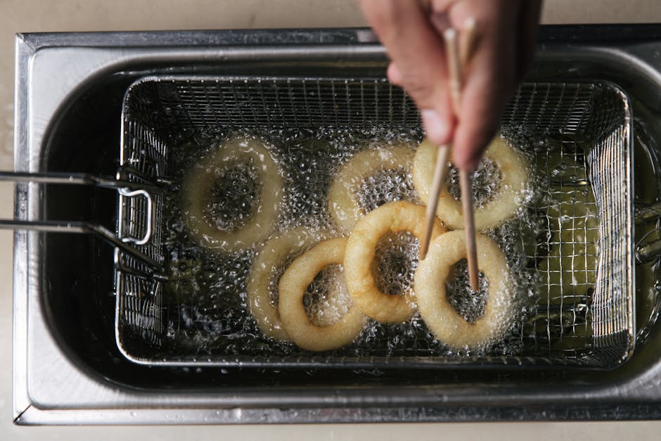 How Air Fryer Basket and Oven Design Impact Cooking Capacity and Crispiness Overhead view of onion rings frying in hot oil with chopsticks in a deep fryer.