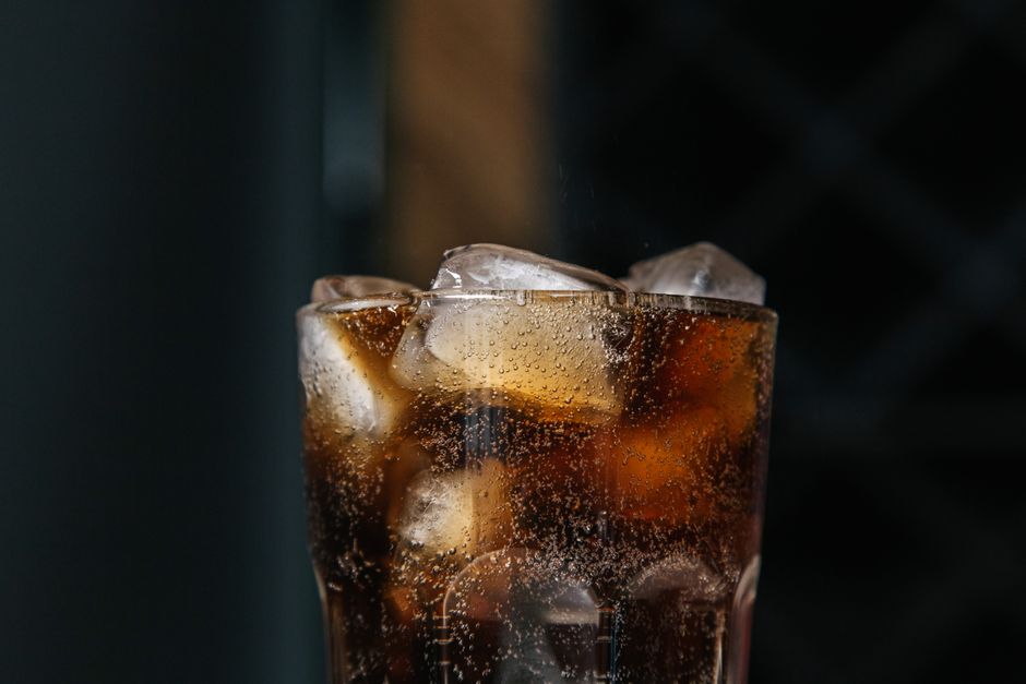 Imagem de um copo com refrigerante escuro e gelo, representando lazer ou momentos de descontração.