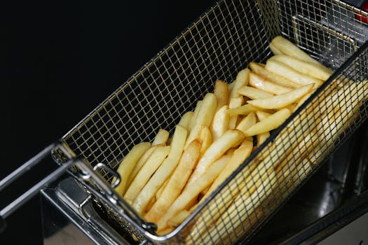 Close-up of freshly fried crispy French fries in a metal basket, highlighting fast food textures.
