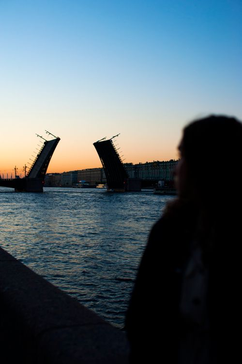Free A drawbridge silhouetted against a beautiful sunset over a river, creating a serene evening scene. Stock Photo