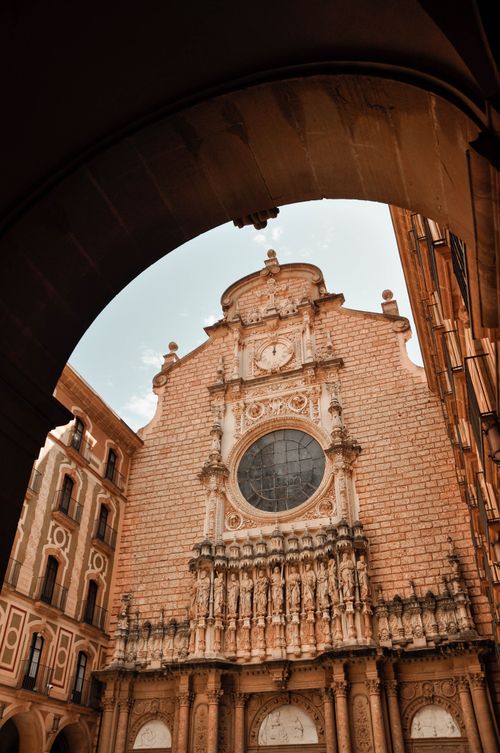 Free Low angle shot of Montserrat Abbey's ornate facade framed by an archway. Stock Photo