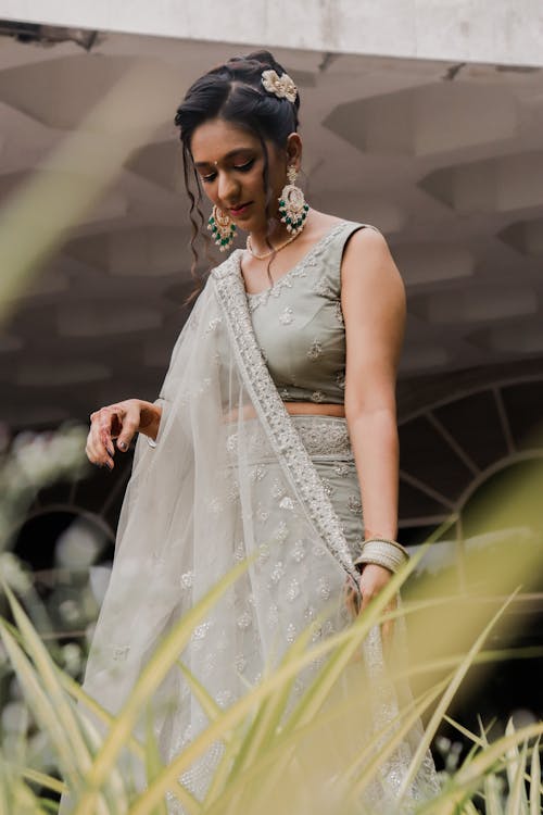 Calm young ethnic woman in Indian bridal gown walking in park
